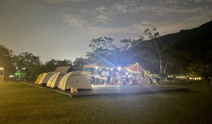 香港汽車露營營地實景:元朗 WeCamp 草地汽車露營區,帳篷旁邊設有戶外枱椅及大片綠色草地,適合朋友圍爐、BBQ 或火鍋聚會