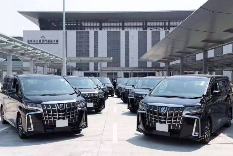 多輛黑色豪華 MPV 商務車在交通樞紐外等候接載，適合中港包車及商務接送服務