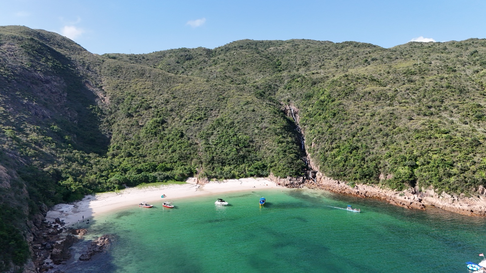 翠綠海灣、沙灘與瀑布的航拍全景